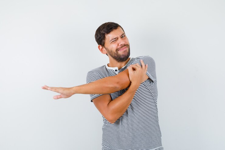 Photo gratuit bel homme étirant les bras en t-shirt et semblant douloureux. vue de face.