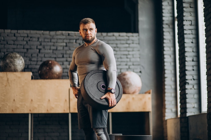 Photo gratuit bel homme fort exerçant au gymnase