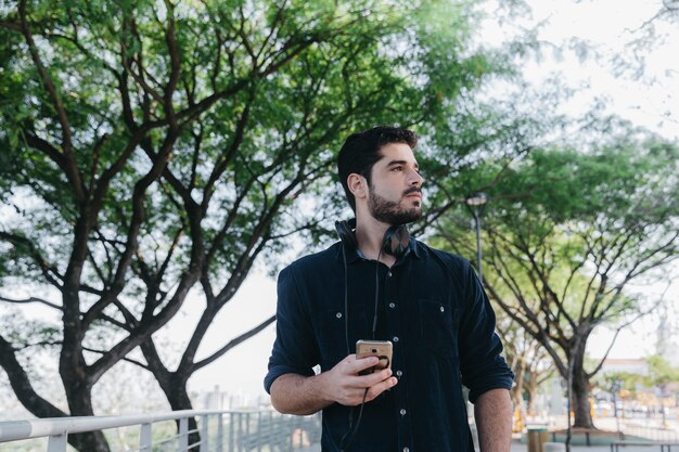 Bel homme avec des gadgets dans le parc