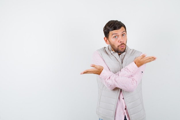 Bel homme en gilet, chemise montrant un geste impuissant et l'air choqué,