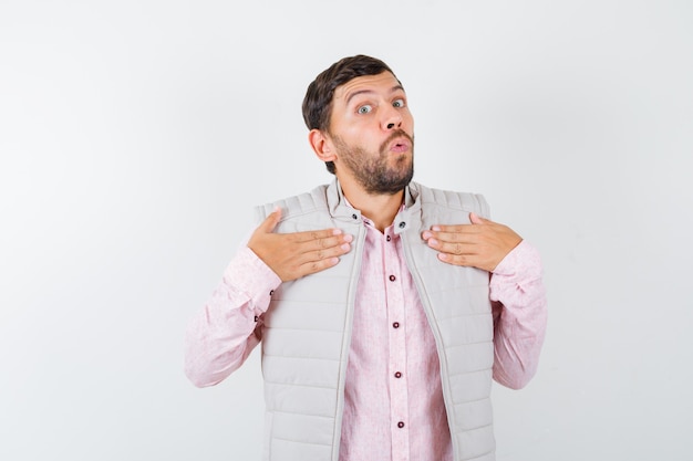 Bel homme en gilet, chemise tenant les mains sur la poitrine et l'air choqué,