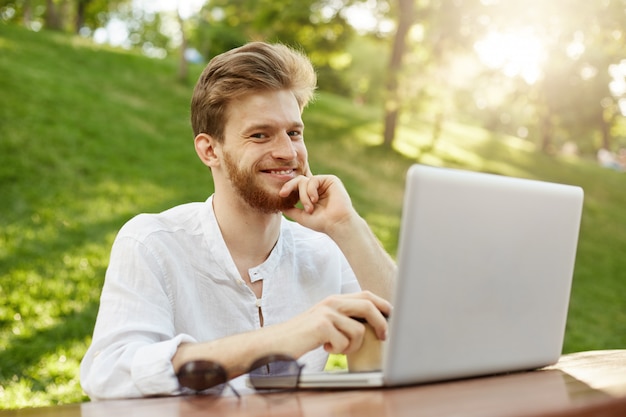 Bel homme gingembre mature avec ordinateur portable dans le parc