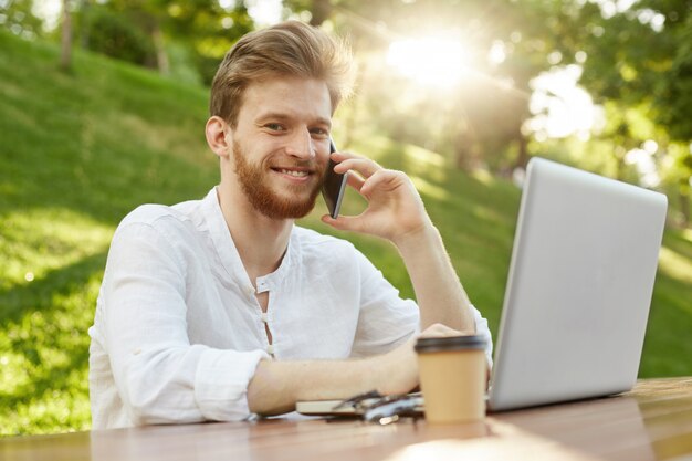 Bel homme gingembre mature avec ordinateur portable dans le parc