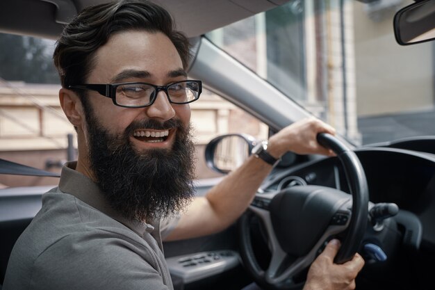 Bel homme heureux au volant de la voiture