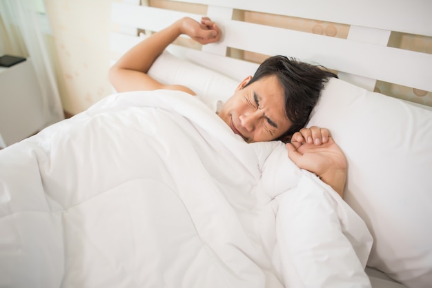 Bel homme heureux se réveiller dans le lit