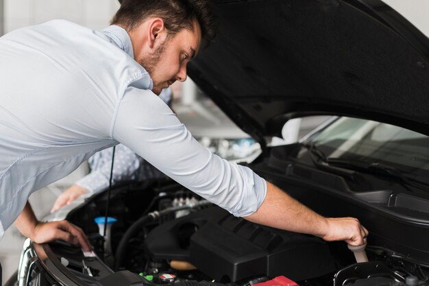 Bel homme inspectant le moteur de la voiture