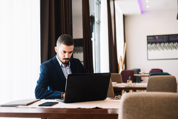 Bel homme à la mode avec gadget au café