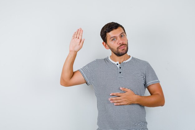 Bel homme montrant sa paume en t-shirt et l'air confiant, vue de face.