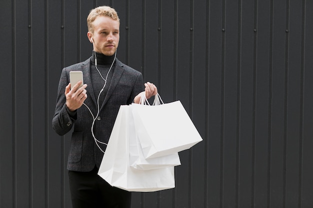 Bel homme en noir avec écouteurs et smartphone