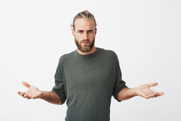 Photo gratuite bel homme nordique avec barbe et coiffure élégante écarte les mains avec une expression cynique et méchante