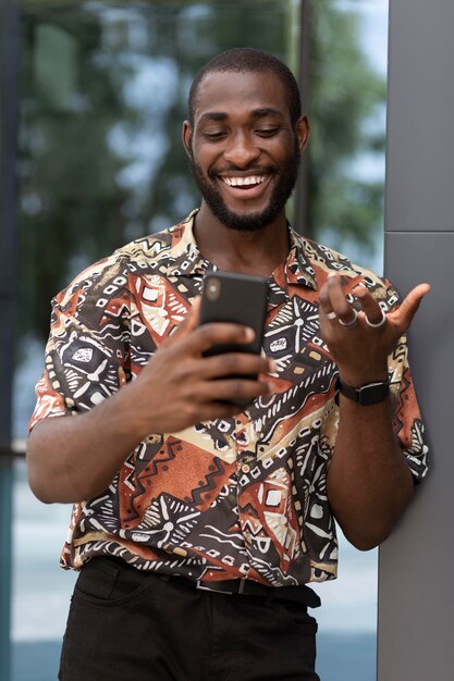 Bel homme passant du temps à l'extérieur et utilisant un smartphone moderne