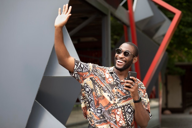 Photo gratuite bel homme passant du temps à l'extérieur et utilisant un smartphone moderne