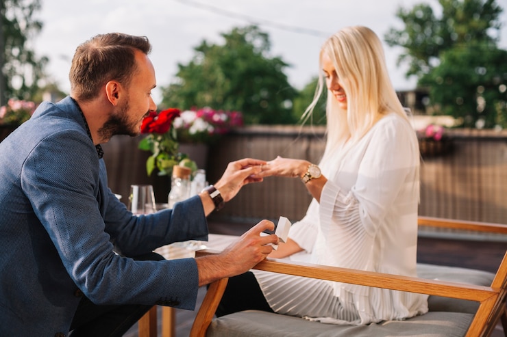 Photo gratuit bel homme plaçant la bague de mariage sur la main d&#39;une femme blonde dans le restaurant