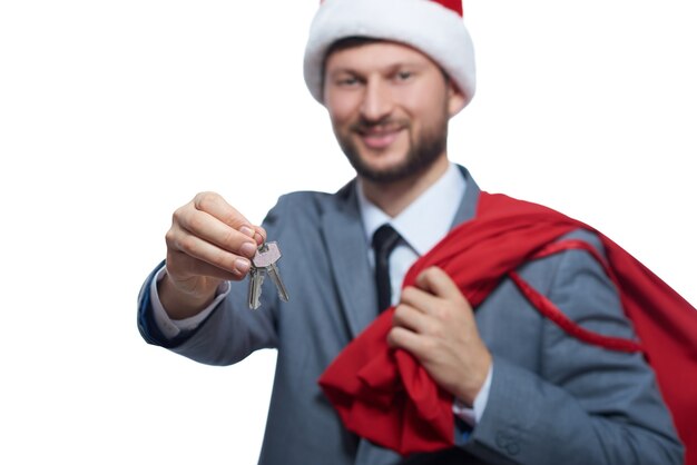 Bel homme portant comme le père Noël donnant la clé de la voiture ou de la maison