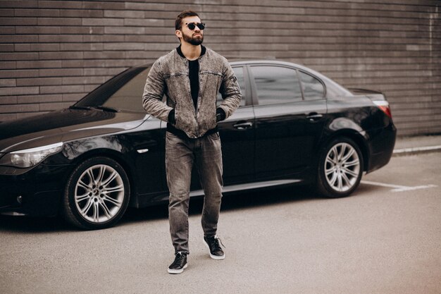 Bel homme posant devant la voiture dans la rue