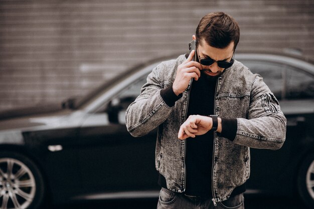 Bel homme posant devant la voiture dans la rue