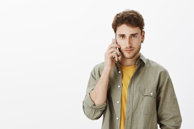 Bel homme posant avec smartphone dans le studio