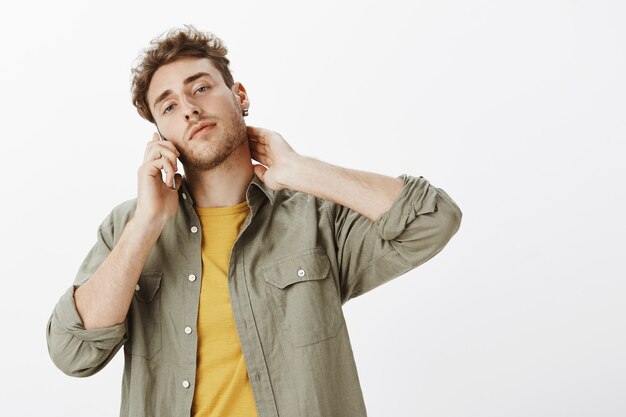 Bel homme posant avec smartphone dans le studio