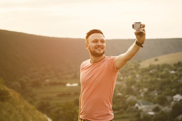 Bel homme prenant des photos de lui-même avec caméra d'action. Filtre instagram vintage rétro