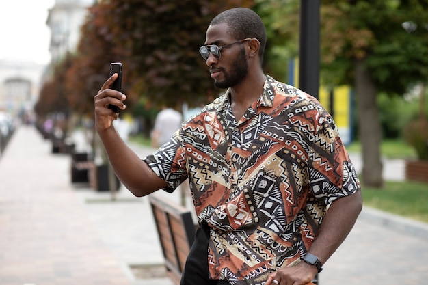 Bel homme prenant selfie avec un smartphone moderne à l'extérieur