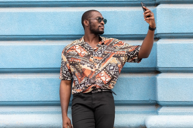 Bel homme prenant selfie avec un smartphone moderne à l'extérieur