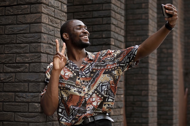 Bel homme prenant selfie avec un smartphone moderne à l'extérieur