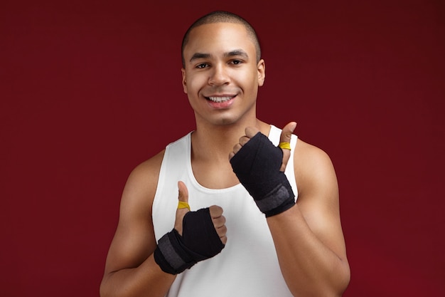 Bel homme de remise en forme tenant une bouteille d'eau et donnant le pouce vers le haut isolé sur fond blanc