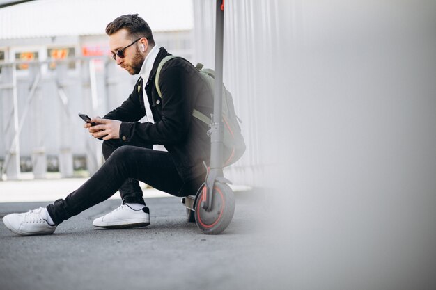 Bel homme sur scooter shopping en ligne sur le téléphone