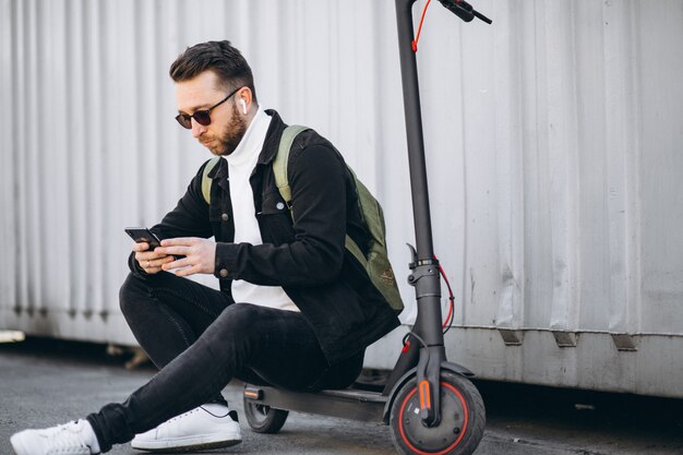 Bel homme sur scooter shopping en ligne sur le téléphone