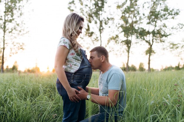 Bel homme se dresse sur les genoux devant un ventre de femme enceinte