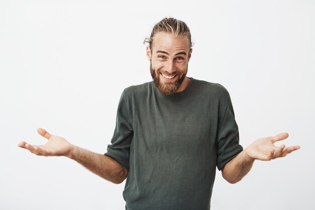 Bel homme souriant et haussant les épaules