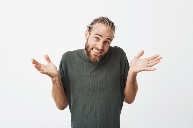 Bel homme souriant et haussant les épaules