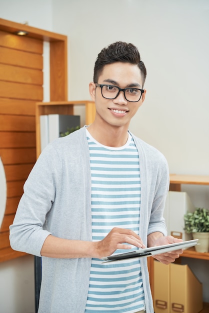 Bel homme souriant avec tablette au bureau