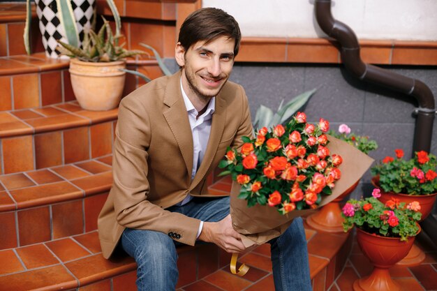 Bel homme souriant tenant un bouquet de roses