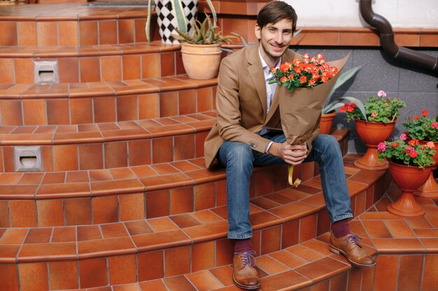 Bel homme souriant tenant un bouquet de roses