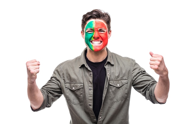Bel homme supporter fan de l'équipe nationale du Portugal peint le visage du drapeau obtenir une victoire heureuse en criant dans une caméra. Émotions des fans.