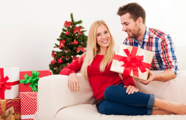 Bel homme surprenant sa petite amie avec un cadeau de Noël