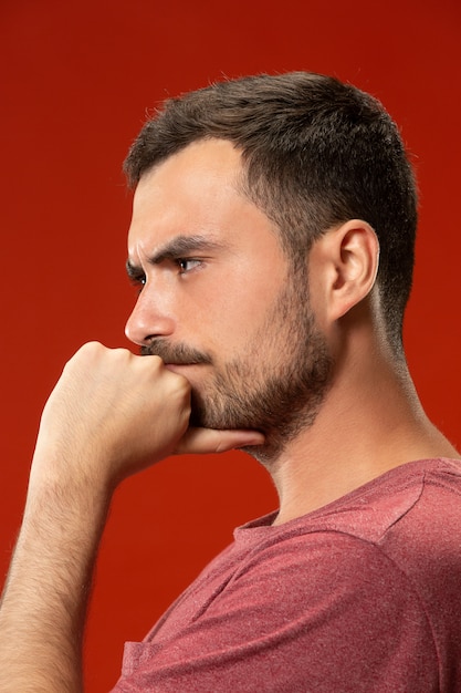 Bel homme à la surprise et perplexe isolé sur rouge