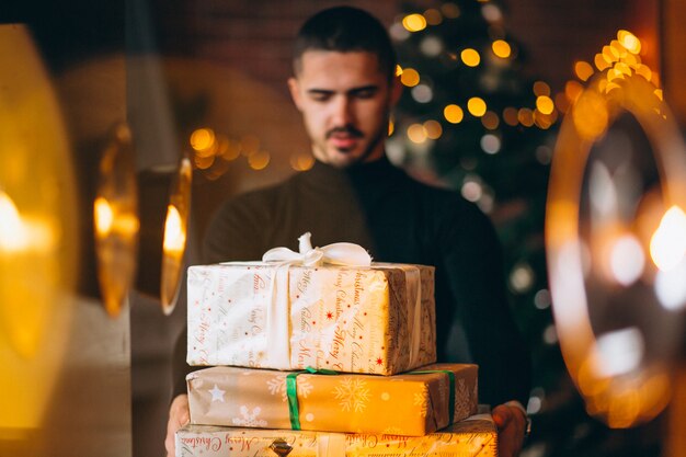 Bel homme tenant des boîtes de cadeaux de Noël