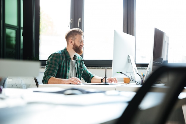 Bel homme travaille au bureau à l'aide d'un ordinateur.