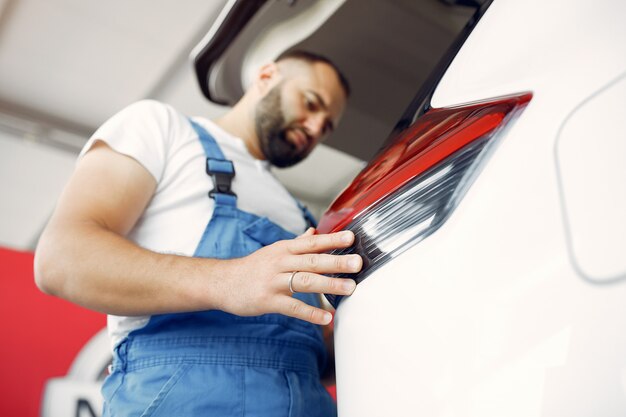 Photo gratuite bel homme en uniforme bleu vérifie la voiture