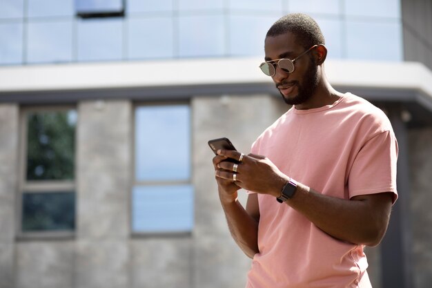 Bel homme utilisant un smartphone moderne à l'extérieur