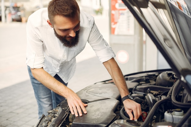 Photo gratuite bel homme vérifie le moteur dans sa voiture