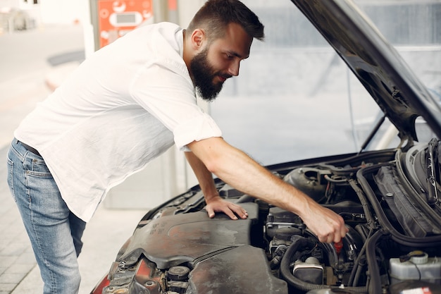 Photo gratuite bel homme vérifie le moteur dans sa voiture