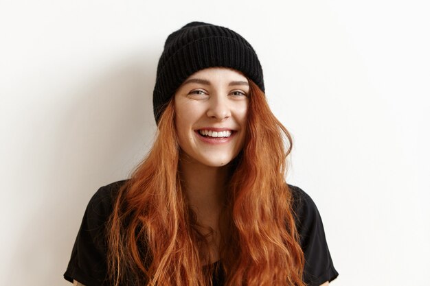 Belle adolescente rousse avec une coiffure en désordre regardant et souriant à la caméra