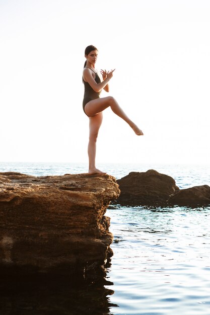 Belle ballerine dansant, posant sur un rocher à la plage