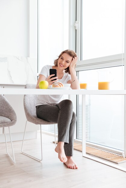 Belle belle femme tenant sa tête tout en lisant le message sur smartphone à la cuisine