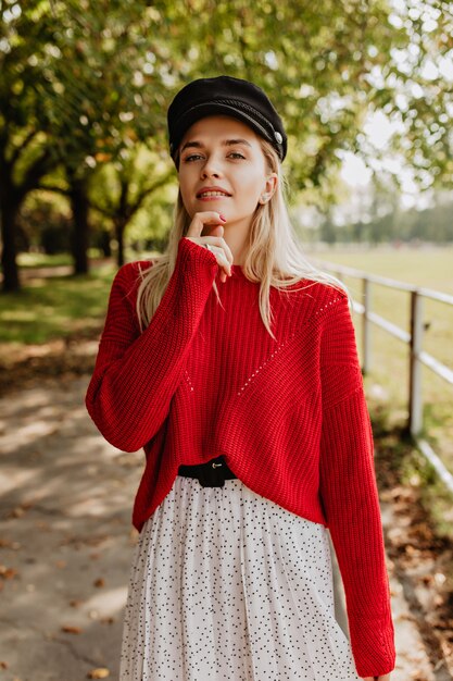 Belle blonde au maquillage naturel regardant tendrement. Joli mannequin en jolie robe posant sur le chemin forestier.