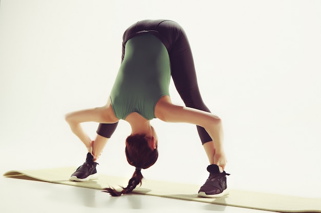 Photo gratuite belle brune mince faisant des exercices d'étirement dans une salle de sport