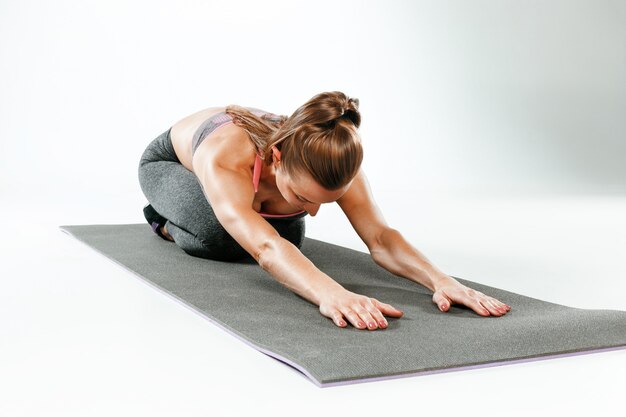 Belle brune mince faisant des exercices d'étirement dans une salle de sport